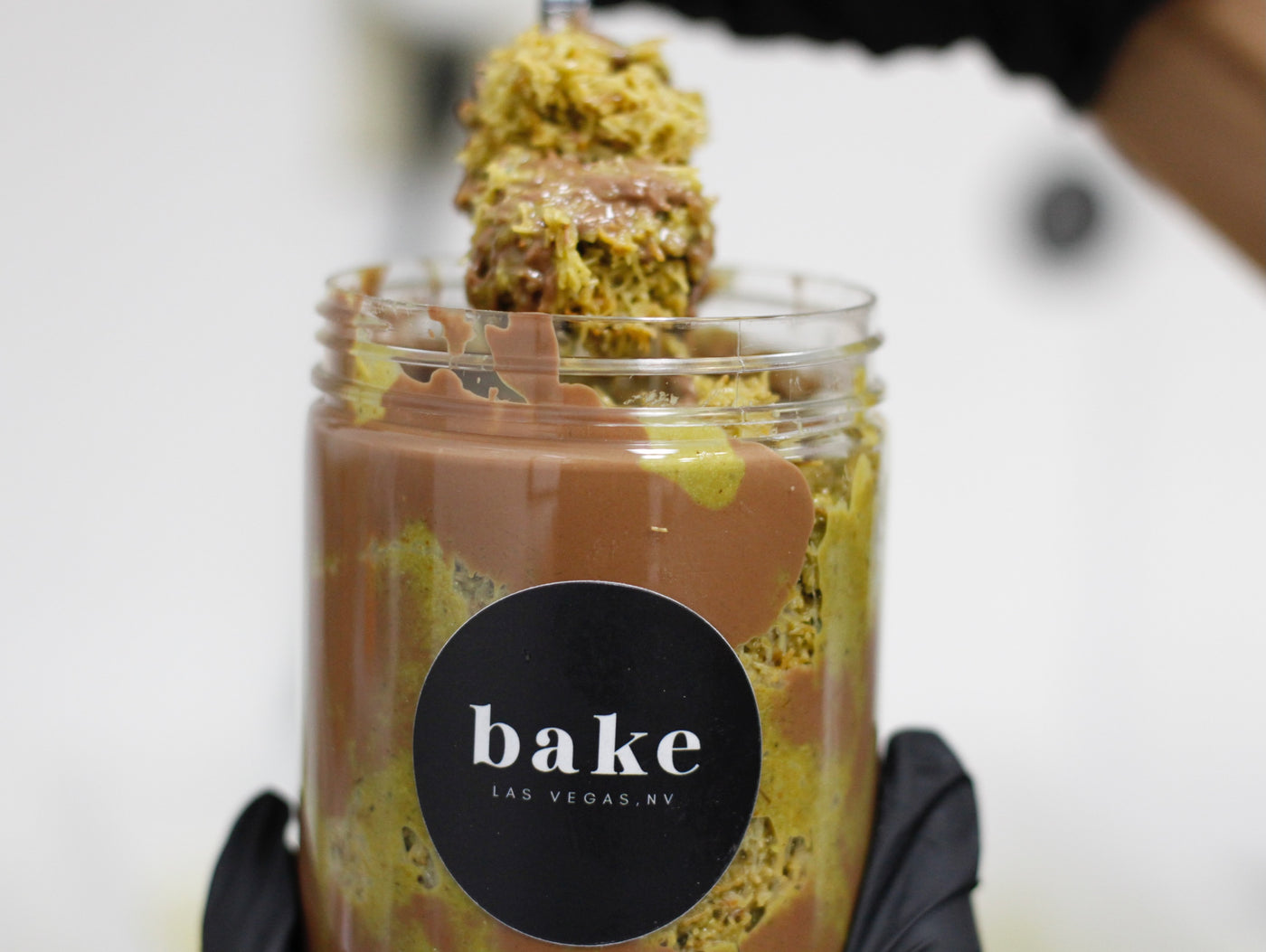 a jar and a spoonfull of Dubai chocolate in a Jar with bake Las Vegas logo