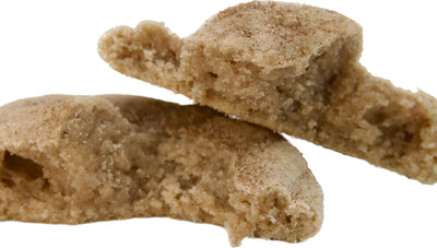 A split snickerdoodle cookie showing the soft and chewy interior with a generous dusting of cinnamon sugar on top