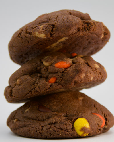 A stack of delicious chocolate peanut butter chip cookies, each filled with a mix of peanut butter chips and Reese's Pieces for the ultimate chocolate and peanut butter experience.